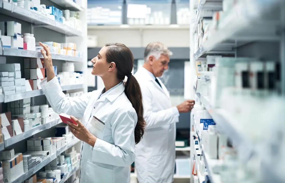Two pharmacists working along the shelves of a hospital pharmacy